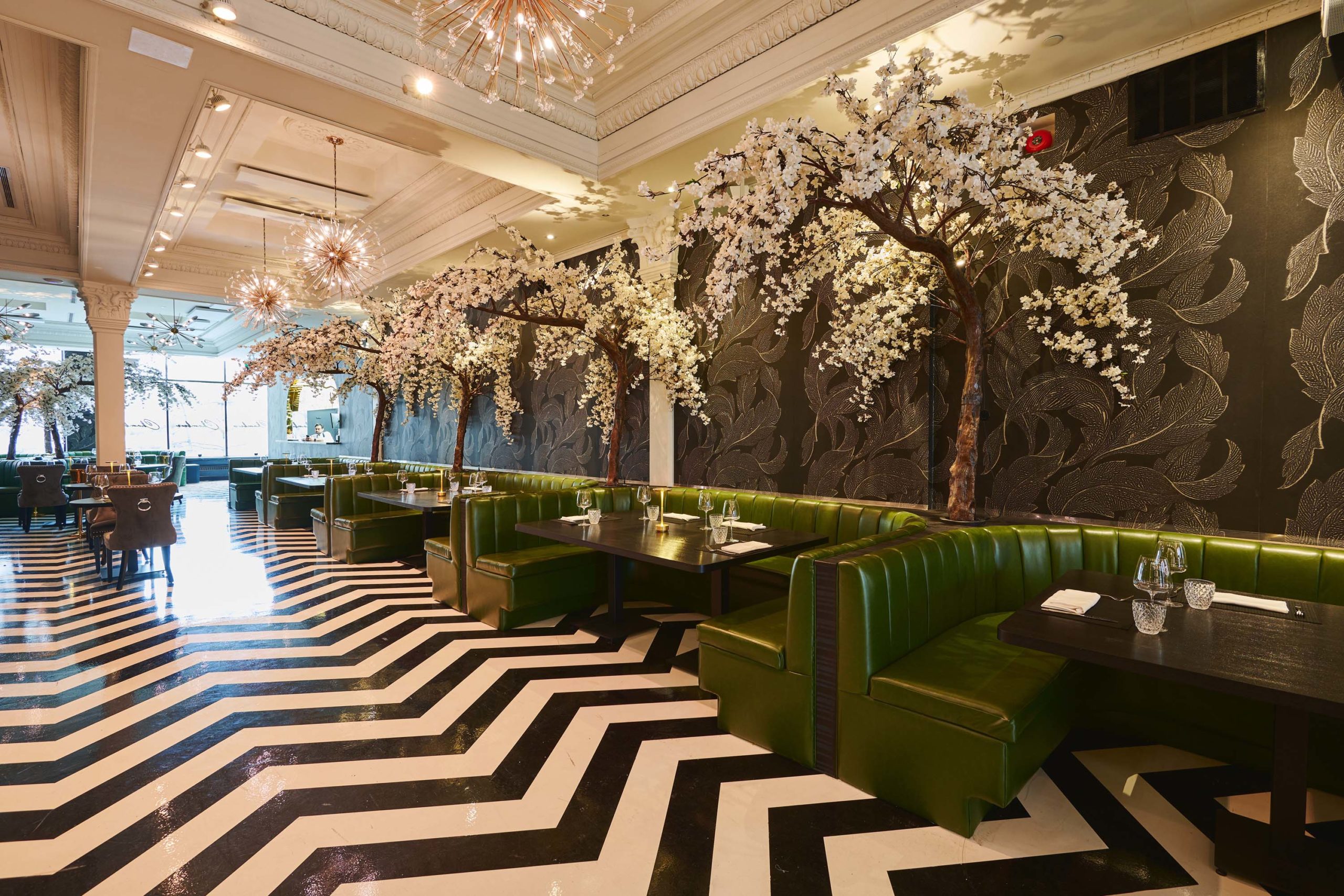 The dining room at Chambers, a fancy new steakhouse and supper club in Toronto, is furnished with green booths and decorated with artificial cherry blossom trees