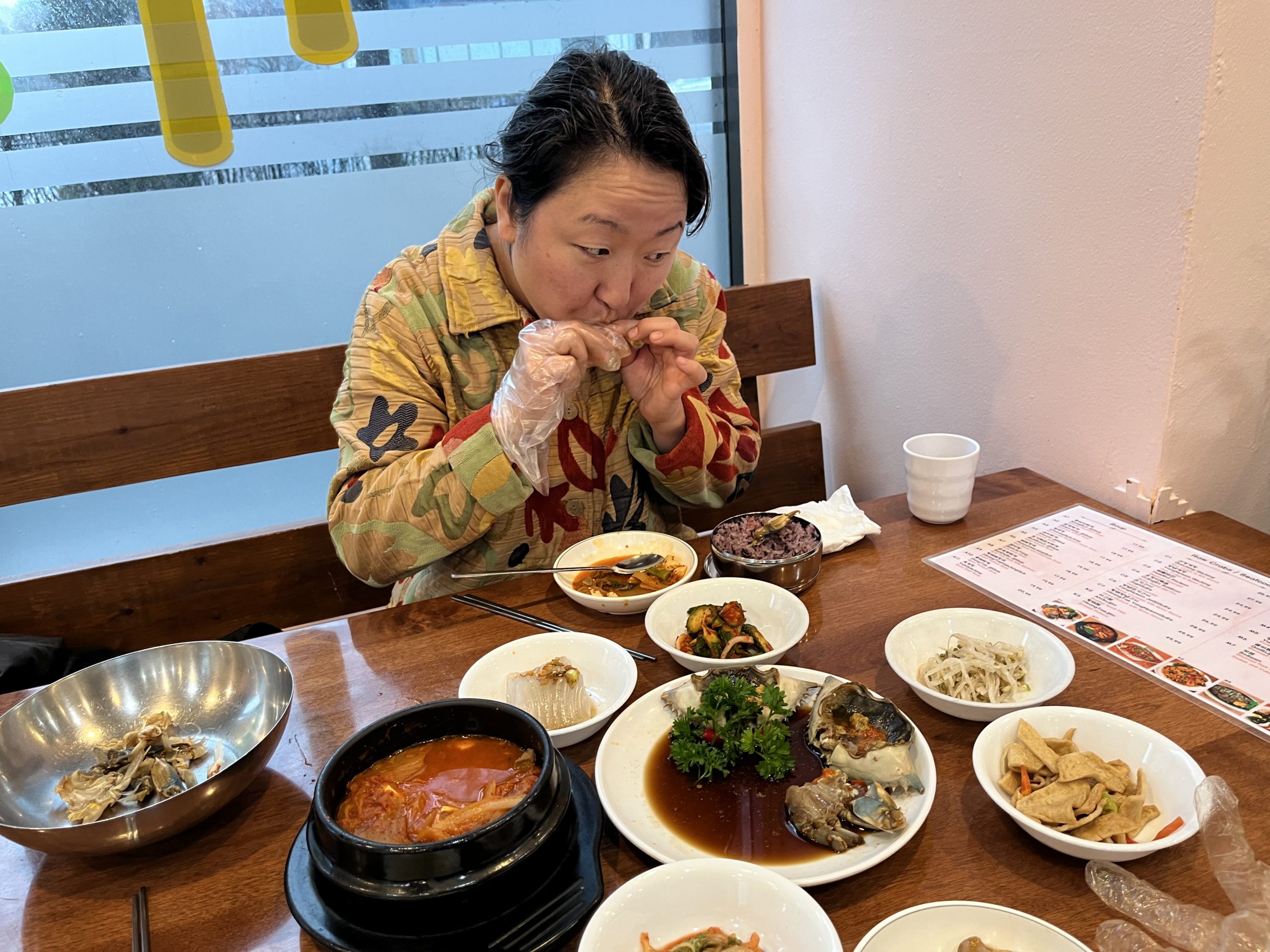Ann Kim uses plastic gloves to eat raw marinated crab at Jungsoonae, a Korean restaurant